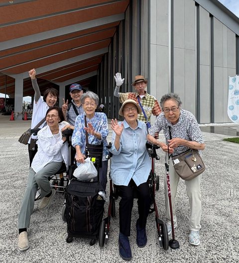 施設の前で笑顔で手を振るグループ